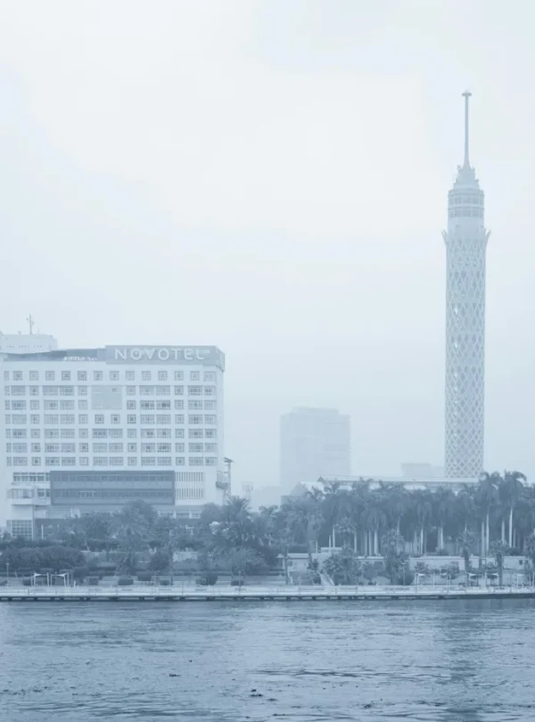 Foggy cityscape of Cairo featuring the Cairo Tower and Novotel by the Nile River.