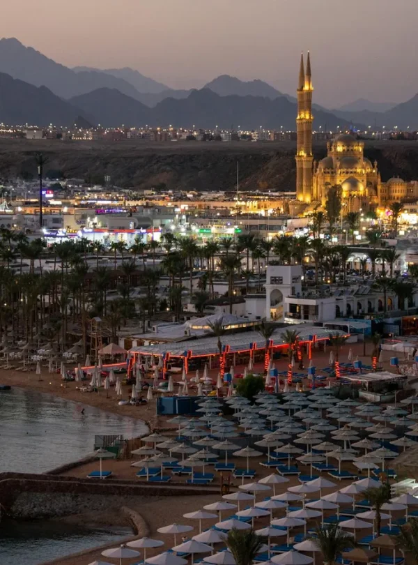 A stunning evening view of the illuminated resort area of Sharm El-Sheikh, Egypt, featuring a lit mosque and surrounding mountains.