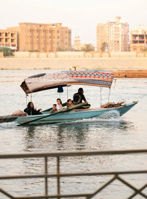 Group enjoying a traditional boat ride on a river with city buildings in the background.