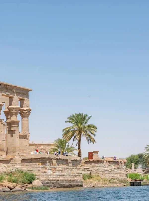 Ancient ruins of Philae Temple by the Nile River under a clear blue sky.