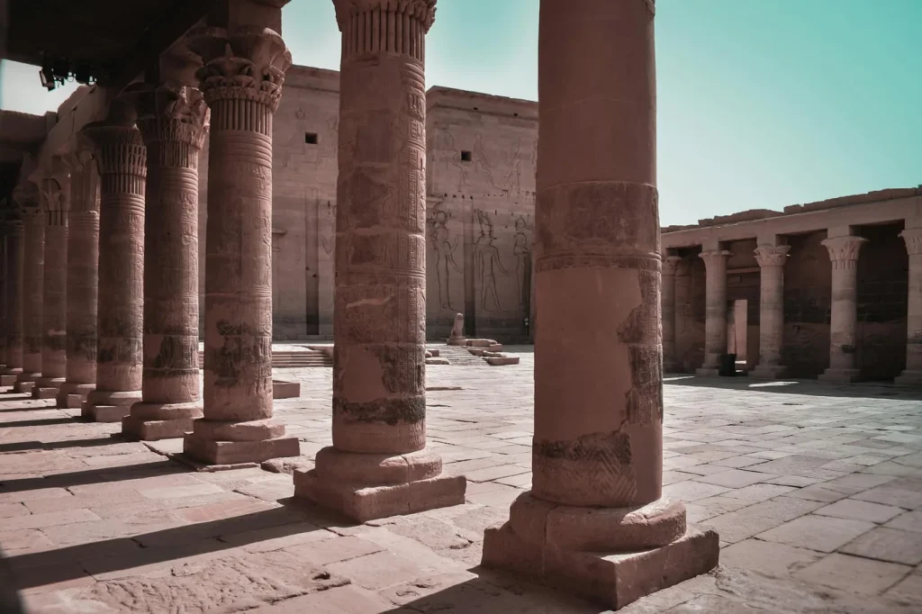 Majestic columns in an ancient Egyptian temple courtyard, Aswan, showcasing intricate carvings.