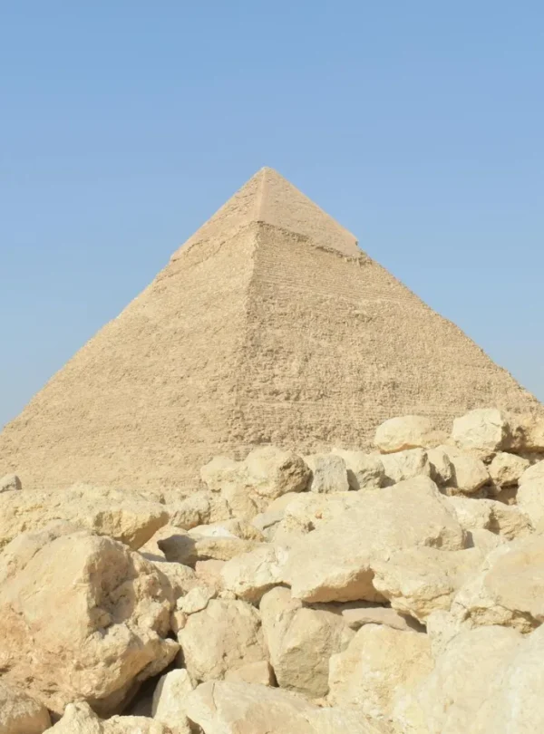 The Great Pyramid of Giza with surrounding stones on a sunny day.