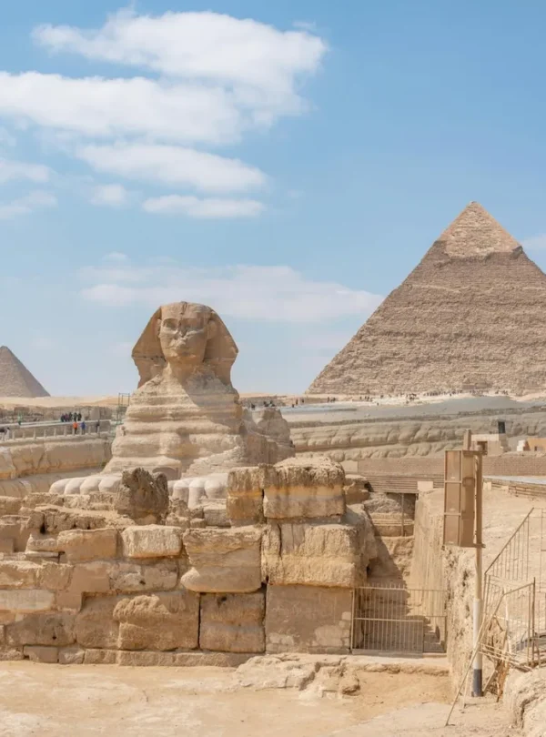 Iconic view of the Great Sphinx and Giza Pyramids in Egypt under a clear blue sky.