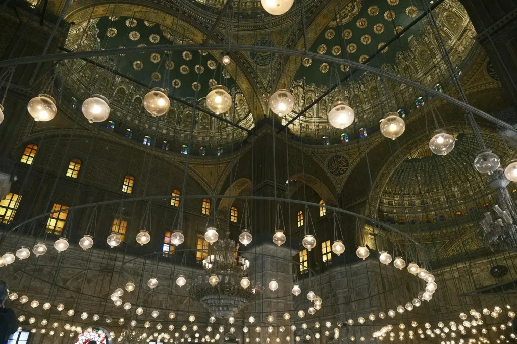 Interior view of a mosque showcasing an intricate dome and chandeliers.