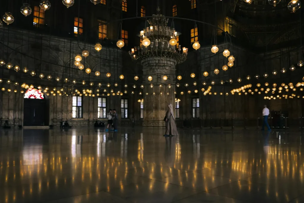Captivating view of mosque interior in Cairo showcasing chandeliers and reflections.
