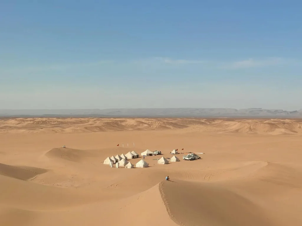 Explore the serene beauty of an isolated desert camp amidst the Sahara dunes in Morocco.