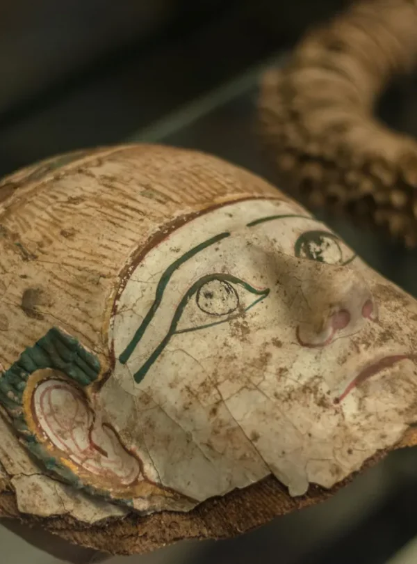 Close-up of an ancient Egyptian mask displayed in a museum exhibit.
