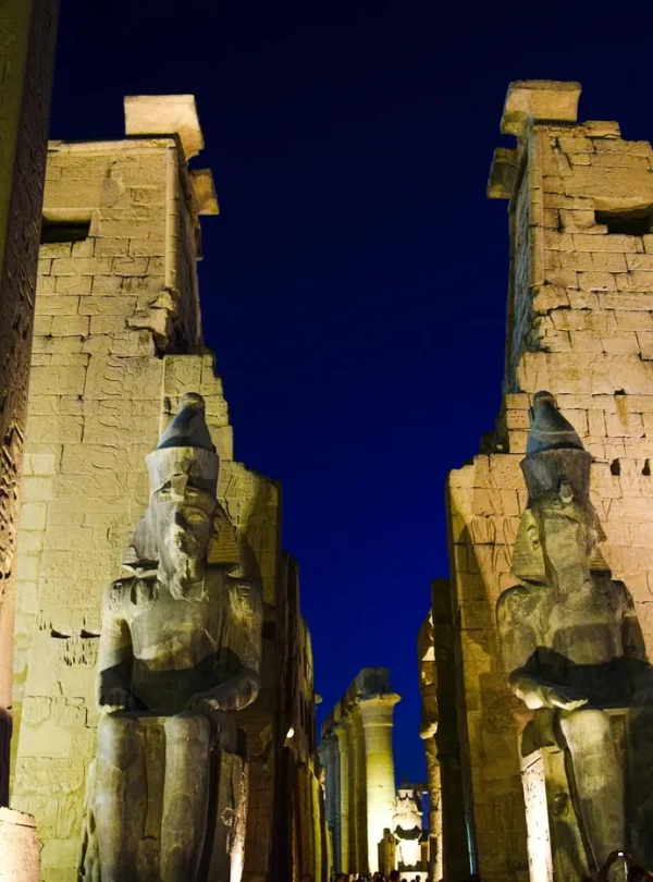 Night view of the illuminated Luxor Temple with ancient statues and hieroglyphs.