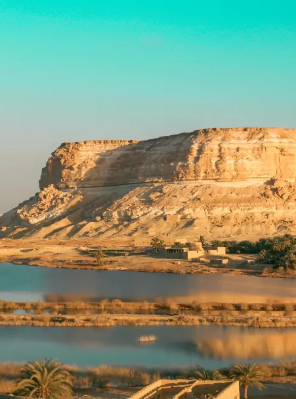 Eroded rock formation by a tranquil lake in a desert landscape, perfect for nature and travel photography.