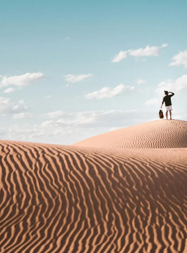 A lone traveler atop a sand dune in Al Wahat Al Dakhla Desert, Egypt.