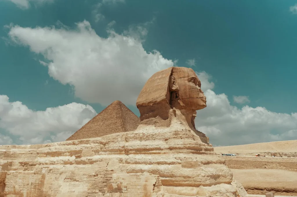 View of the Great Sphinx and a pyramid in Egypt under a clear blue sky.