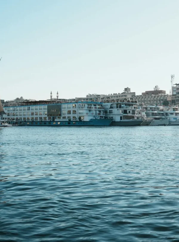 A picturesque view of a traditional sailboat on the Nile River near city waterfronts.