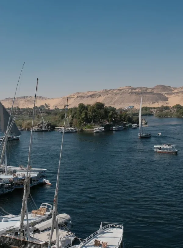 Steamboats and sailboats navigate the scenic Nile River with desert hills in the background, Egypt.