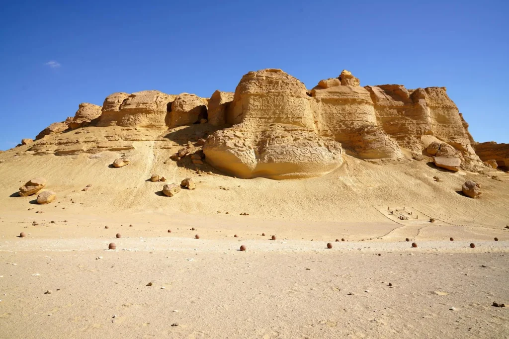 Magnificent sandstone cliffs under the vibrant blue sky in Egypt's desert.